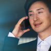 Confident asian businessman talking on mobile phone on blurred background.
